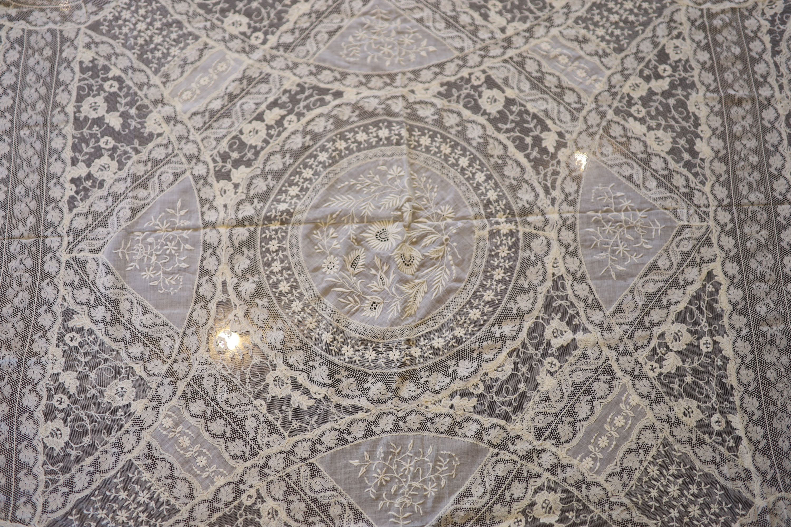 A square Normandy lace table cloth and approximately nineteen circular place mats and a centrepiece,